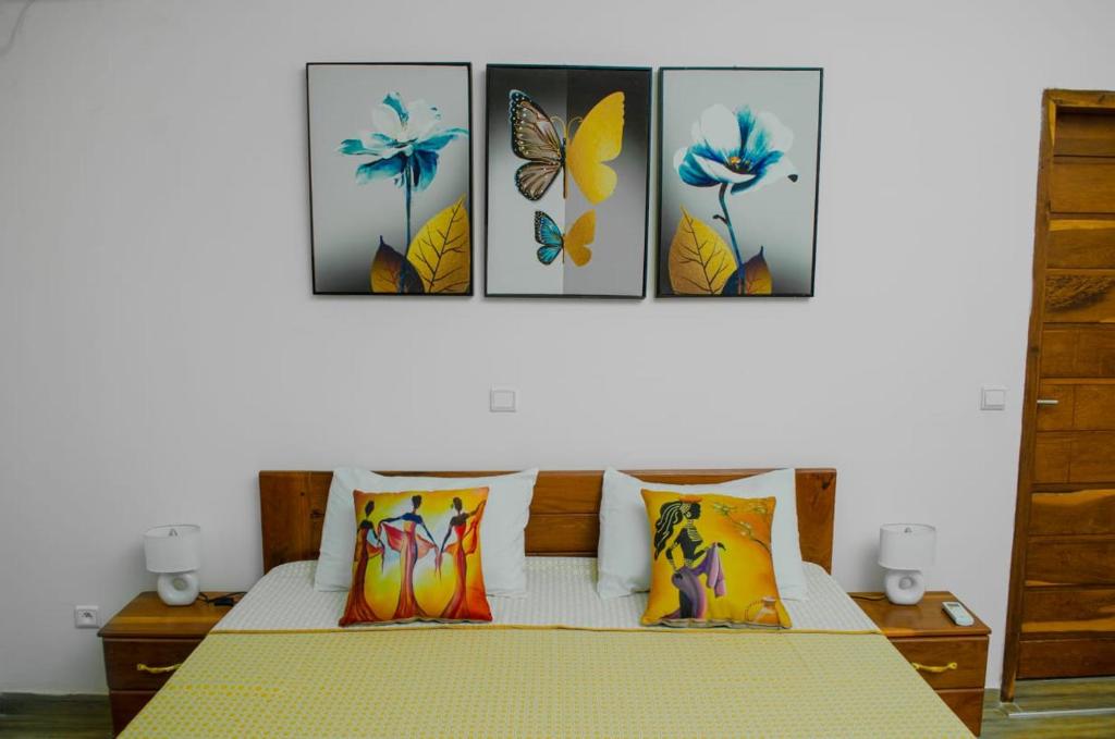 um quarto com uma cama com quatro fotografias na parede em Residence Eliz em Kabrousse
