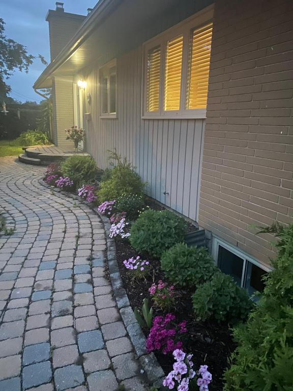 a house with a brick walkway next to flowers at Spacious Guest house -walkout Basement- 4 guests! -dedicated workspace-No Pet! No Cooking! No Smoking! No Party! in Ottawa