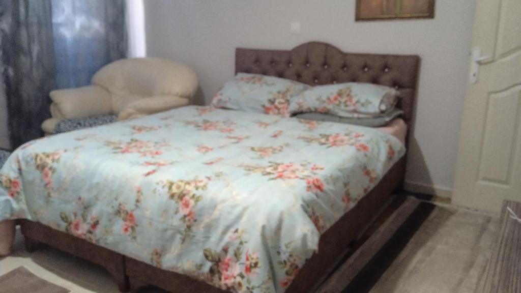 1 cama con edredón de flores y 1 silla en el dormitorio en BE MY GUEST - Homestay ApartmentS Guest HouseS Sleeping Rooms, en Antalya