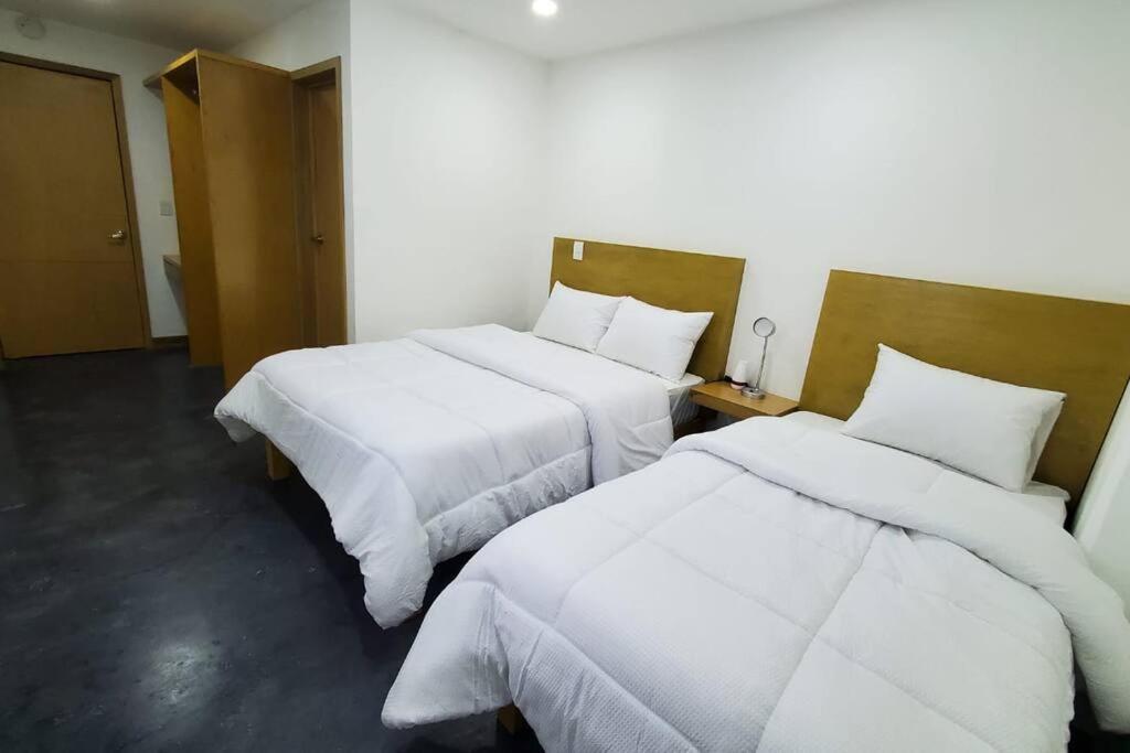 Habitación de hotel con 2 camas con sábanas blancas en El lugar perfecto para descansar.²⁰⁸, en Fortín de las Flores