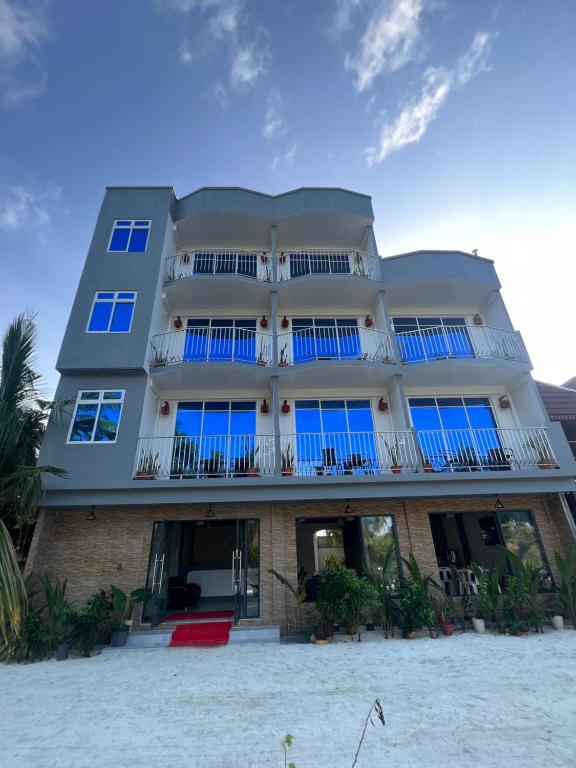 圖杜的住宿－Rihiveli Residence Thoddoo，海滩上一座带蓝色窗户的大型建筑