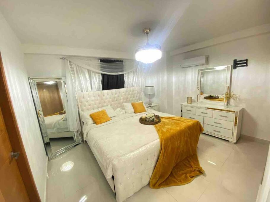 a bedroom with a large white bed and a mirror at AM.AIRBNB in Santo Domingo