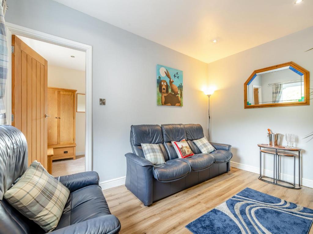 a living room with a leather couch and a mirror at Woodlands Barn in Chinley