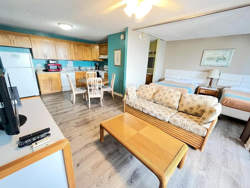 a living room with a couch and a kitchen at Royal Kuhio 1702 - Spacious Studio with Stunning Mountain City Views in the Heart of Waikiki! in Honolulu