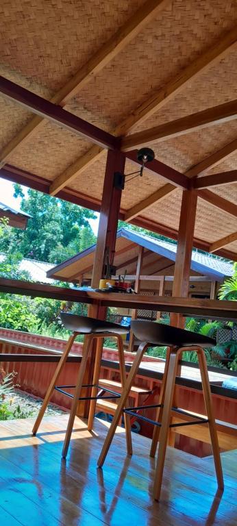 a wooden table with two chairs under a roof at At Home in Puerto Princesa City