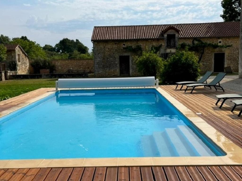 una piscina con terrazza in legno e una casa di Gîte Savignac-les-Églises, 4 pièces, 8 personnes - FR-1-616-216 a Savignac-les-Églises
