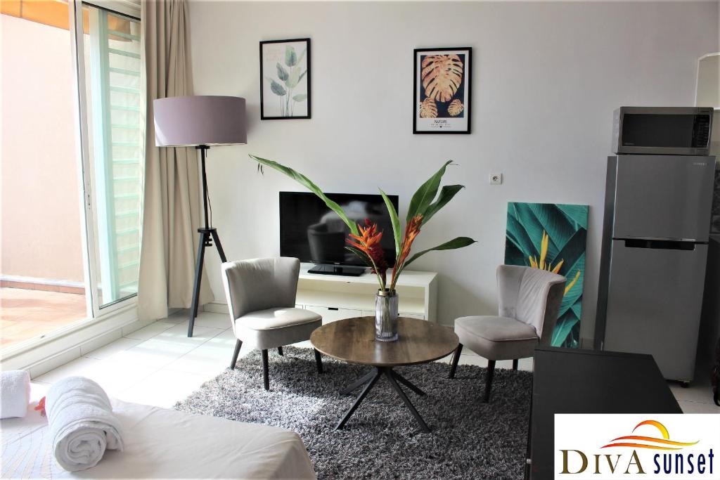 a living room with a table and chairs and a tv at Tahiti Diva Sunset studio in Papeete