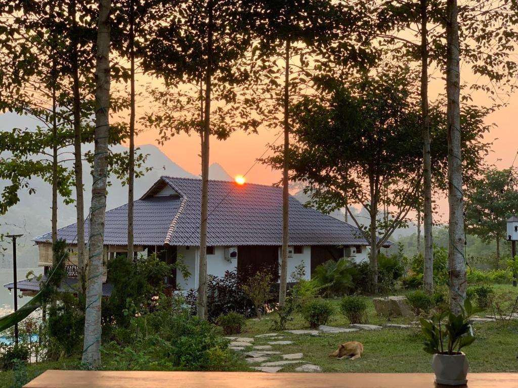 une maison avec un chien assis devant elle dans l'établissement Hồ Tằm Homestay, à Hòa Bình