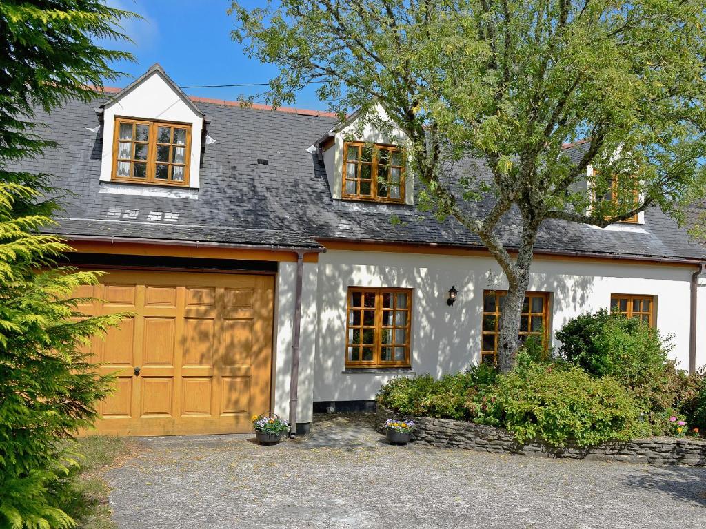 a white house with a brown garage at Lanacre Cottage in Mylor Bridge