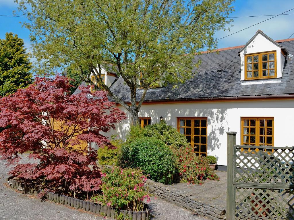 a white house with trees and bushes in front of it at Lanacre Cottage in Mylor Bridge