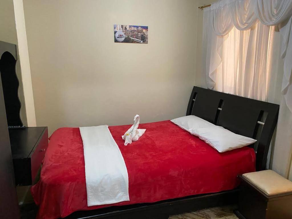 Un dormitorio con una cama roja y blanca con un pájaro. en Hotel Casa Real 2, en Popayán