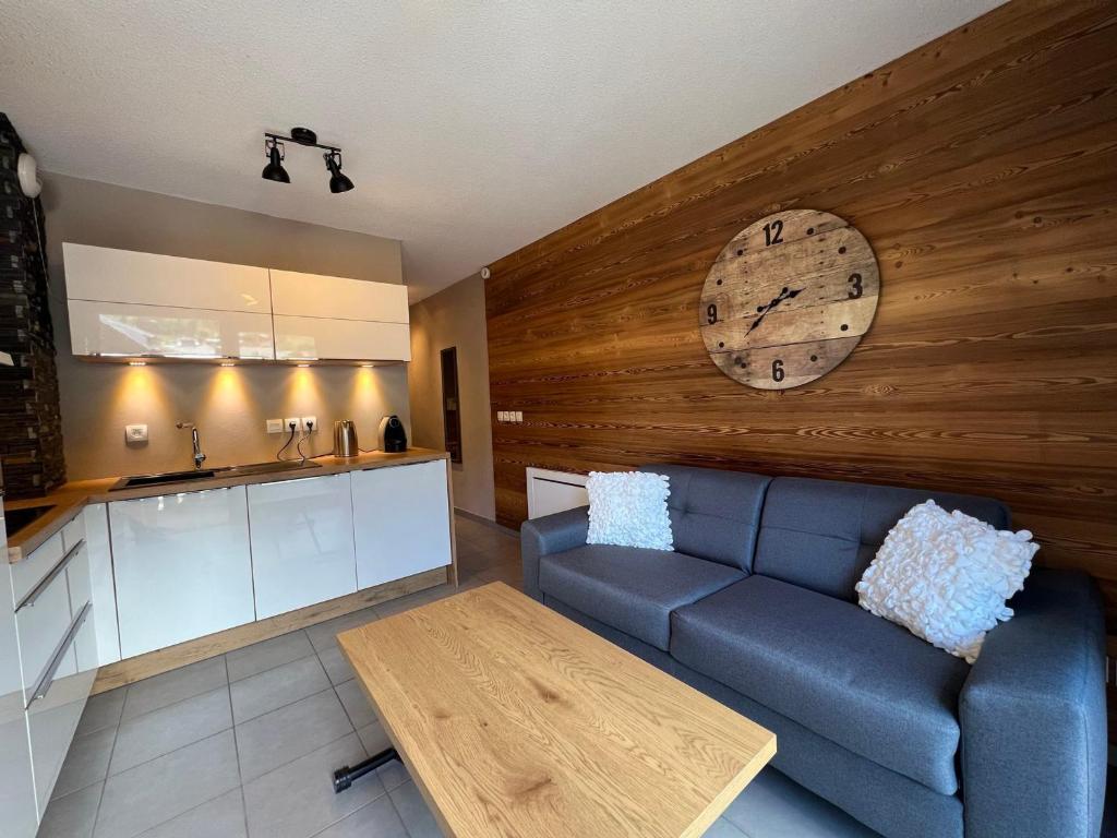 ein Wohnzimmer mit einem Sofa und einer Uhr an der Wand in der Unterkunft Studio Les Gets, 1 pièce, 4 personnes - FR-1-623-194 in Les Gets