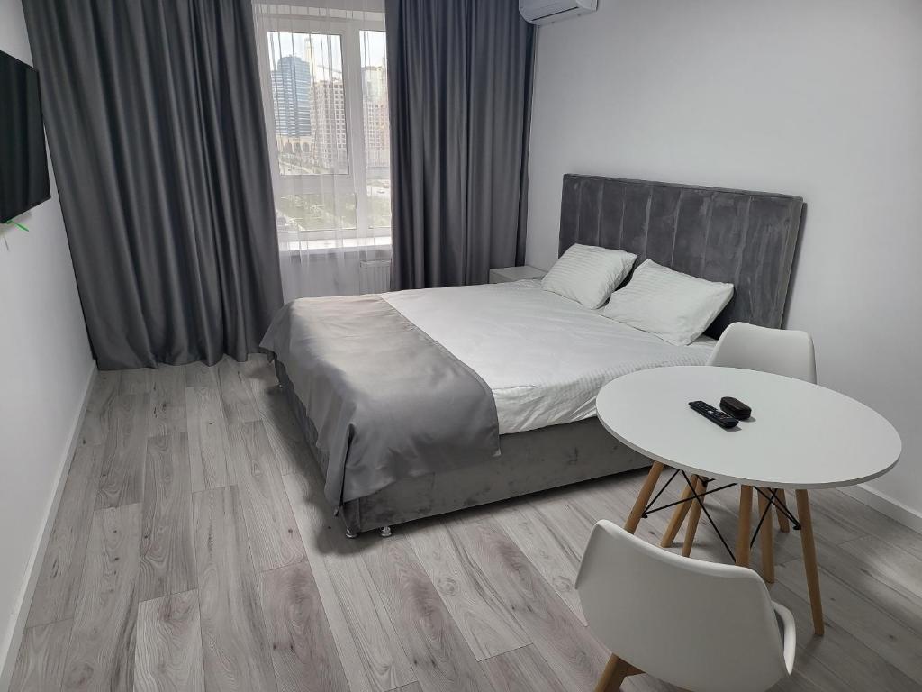 1 dormitorio con 1 cama, mesa y sillas en Толе Би 57 - ТРЦ Хан Шатыр, en Astana