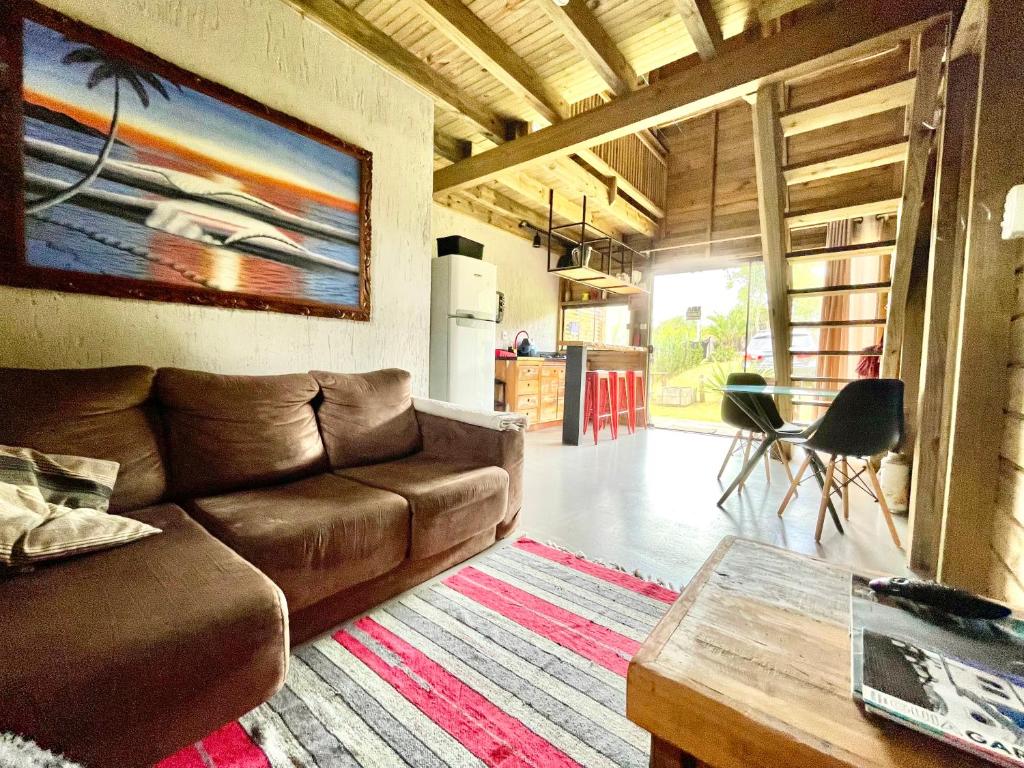 a living room with a brown couch and a table at Rosa Lodge Lofts in Praia do Rosa