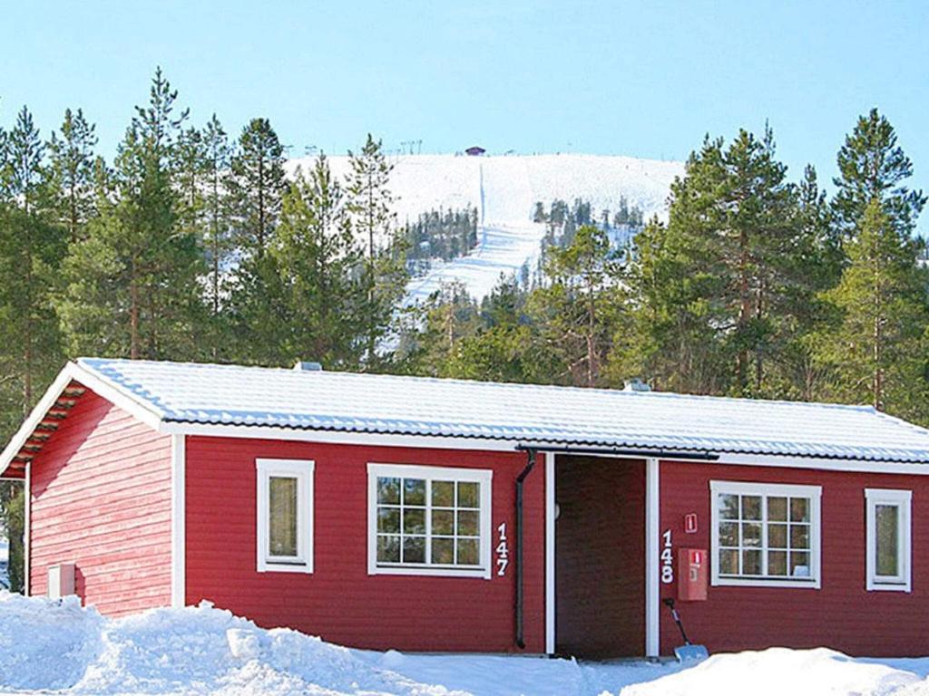 une maison rouge dans la neige avec des arbres et une colline dans l'établissement Holiday home SÄLEN, à Stöten