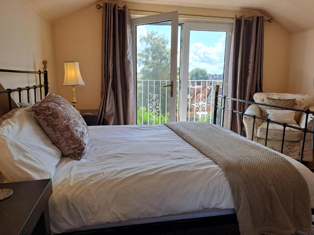 1 dormitorio con 1 cama grande y ventana en Maidenhead House Serviced Accommodation in quiet residential area, free parking, 3 bedrooms, WiFi 1 Gbps, work desks, office chairs, TV 55" Roku, Company stays, couples and families welcome, sleeps 6 en Maidenhead