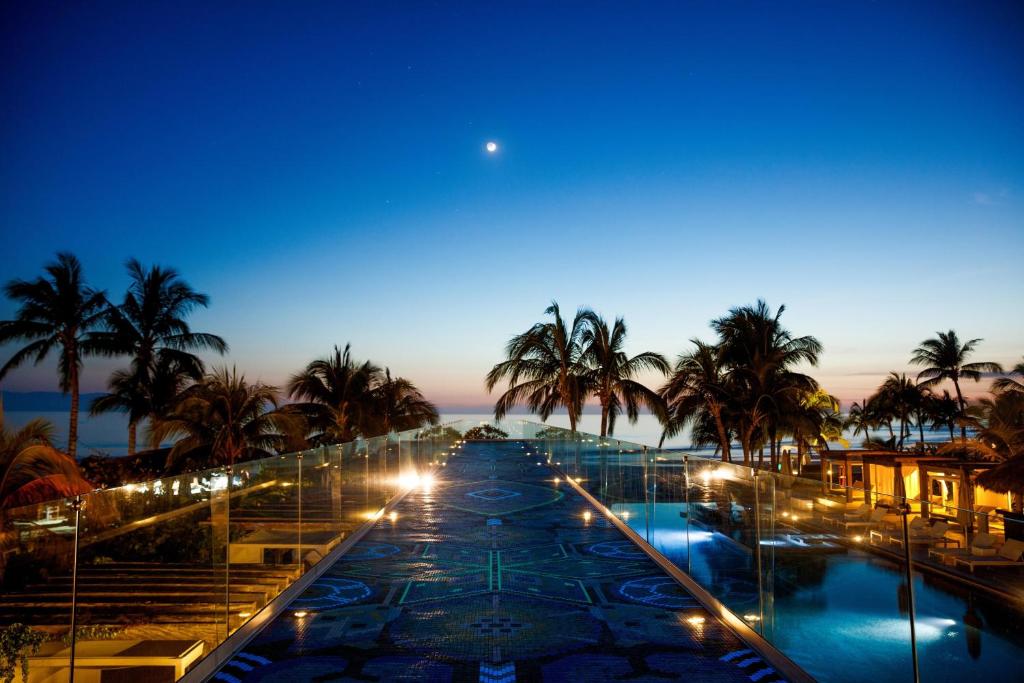 uma vista para uma piscina com palmeiras à noite em W Punta de Mita em Punta Mita