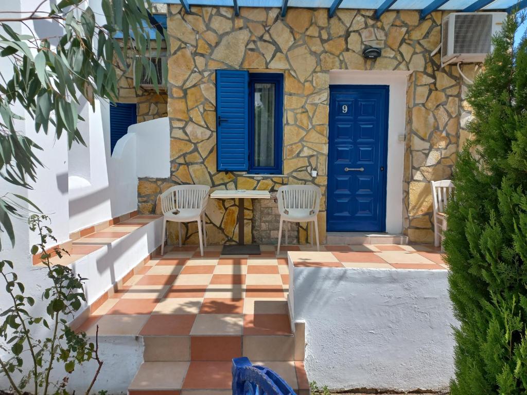 a stone house with blue doors and chairs on a patio at Serifos Palace in Livadakia