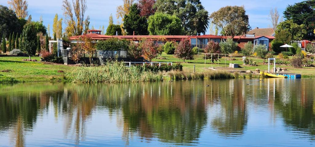 a view of a lake with a house in the background at New Horizons Farm Stay in Smeaton