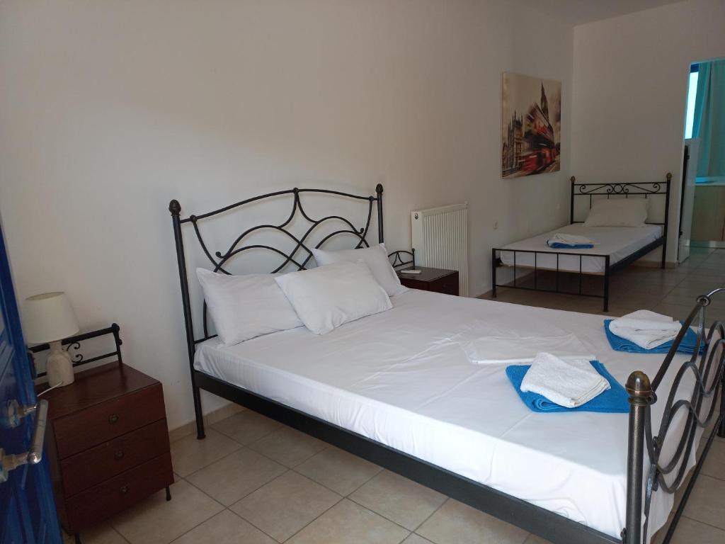 a bedroom with a bed with white sheets and blue towels on it at Serifos Palace in Livadakia