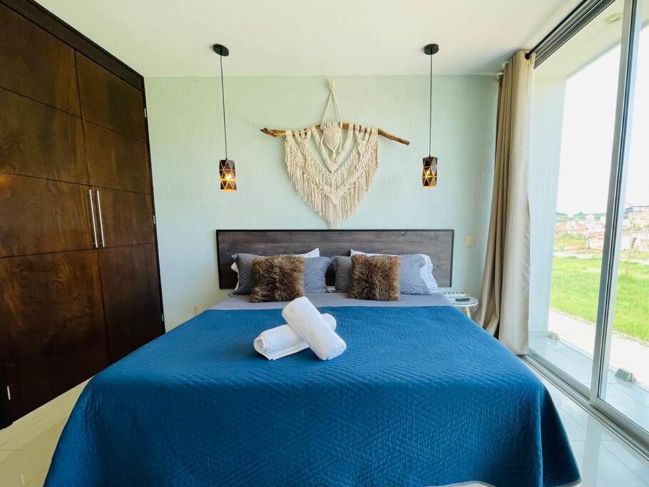 1 dormitorio con 1 cama azul y 2 toallas en Magnolia A Luxury stay 5 minutes from Downtown, en Tepatitlán de Morelos