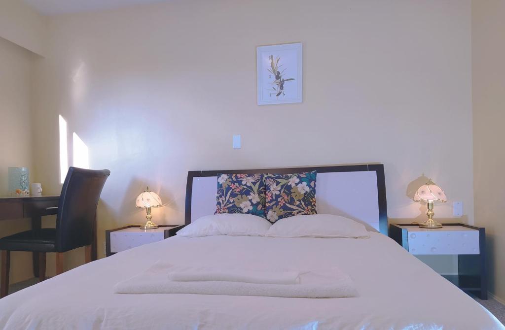 een slaapkamer met een wit bed met 2 tafels en 2 lampen bij Master room &full bathroom with separate entrance in richmond in Richmond