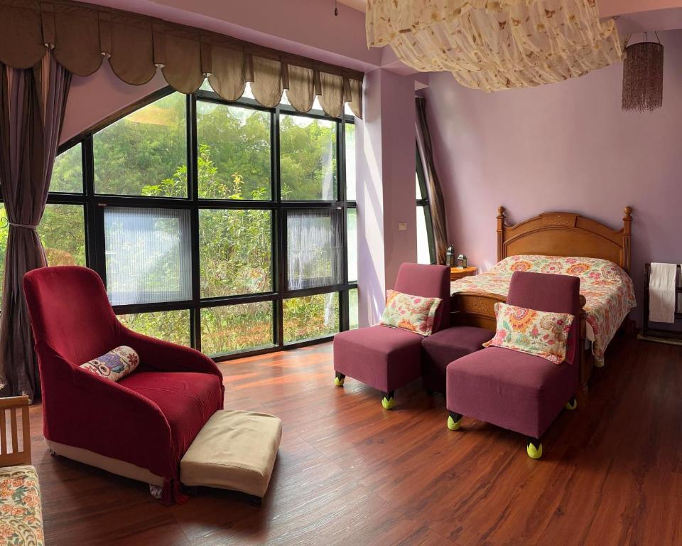 a bedroom with a bed and chairs and windows at Maison-Philo Homestay B & B in Sanyi