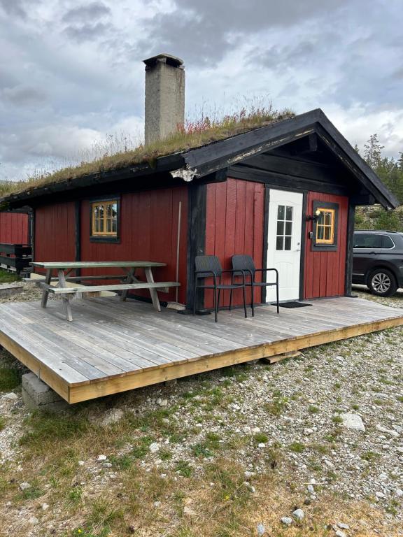 czerwona kabina z tarasem, stołem i krzesłami w obiekcie Atnasjø Kafe AS w mieście Sollia