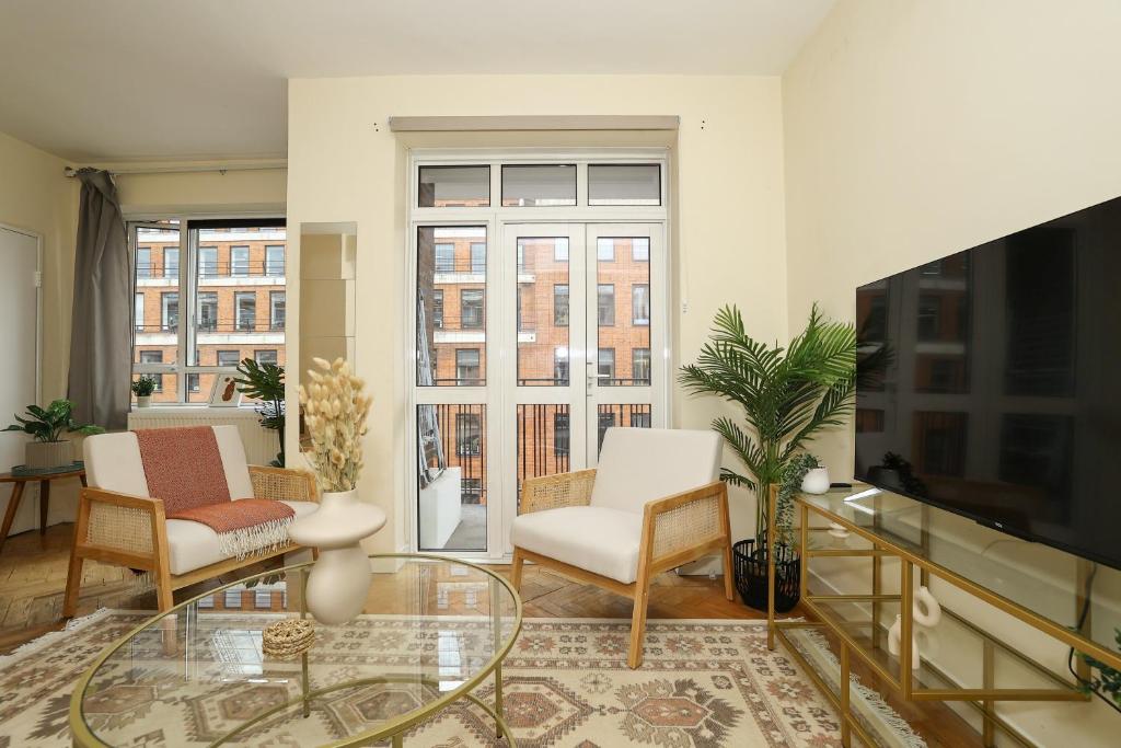 a living room with two chairs and a tv at Spacious 2 bedroom Apartment In Holborn in London