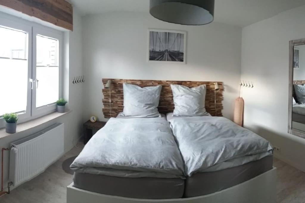 um quarto com uma cama grande com lençóis brancos e almofadas em Ferienwohnung Zum Wenning mit Garten in Stadtlohn em Stadtlohn