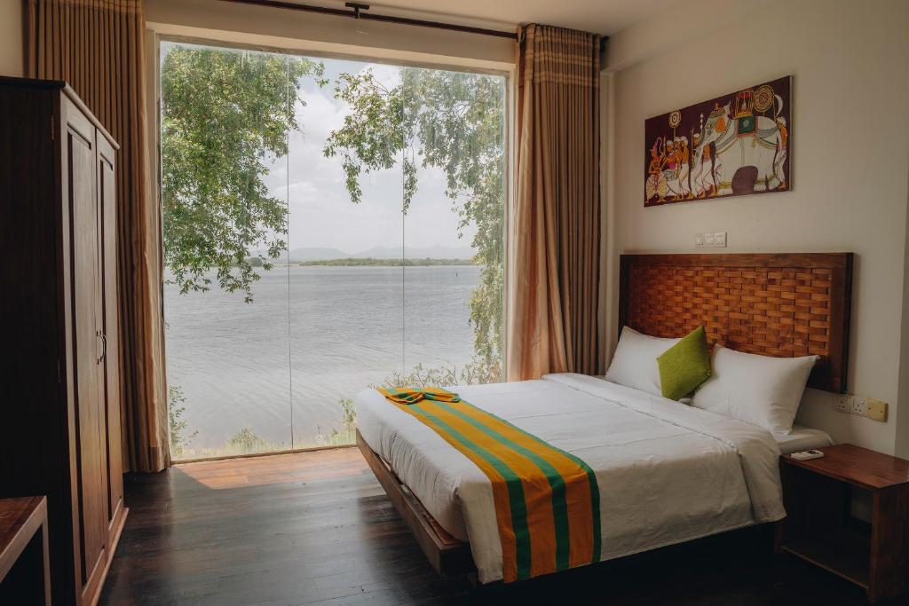 a bedroom with a bed and a large window at Yala Oga Reach Hotel in Tissamaharama