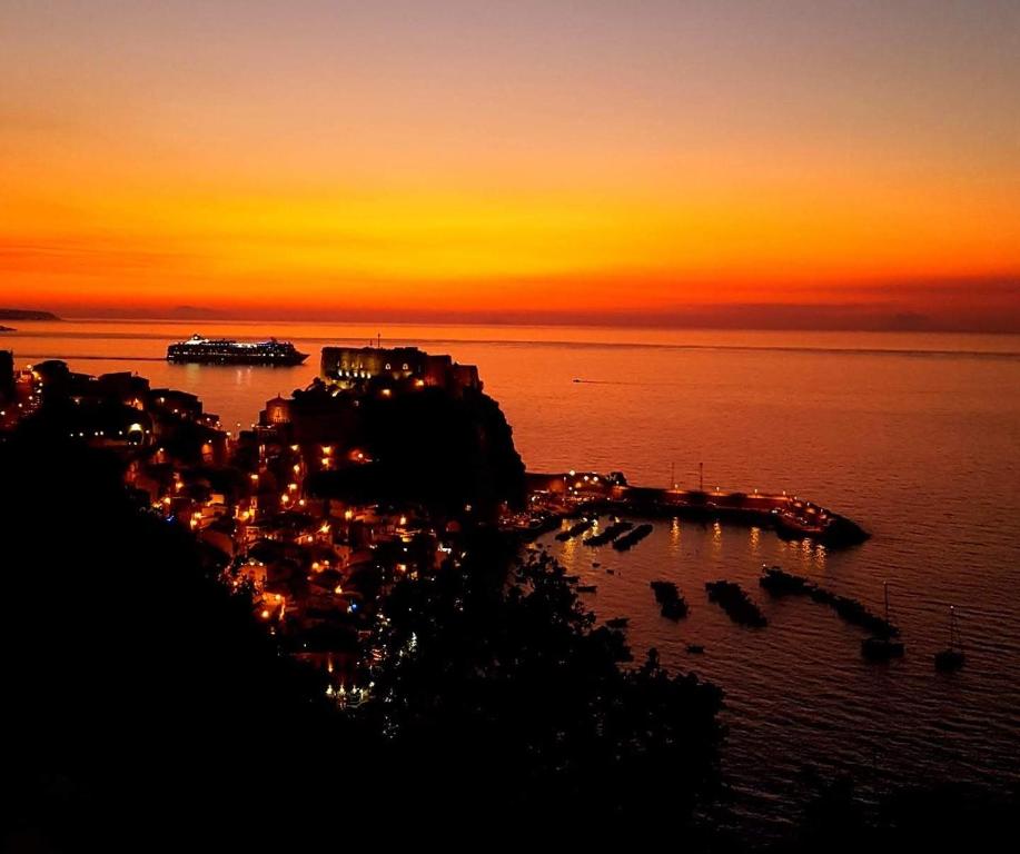 a sunset over a city with boats in the water at Brezza Marina in Scilla