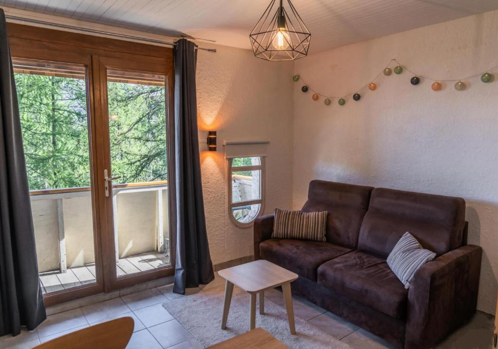 a living room with a brown couch and windows at Résidence L'horizon - Studio pour 4 Personnes 584 in Les Orres
