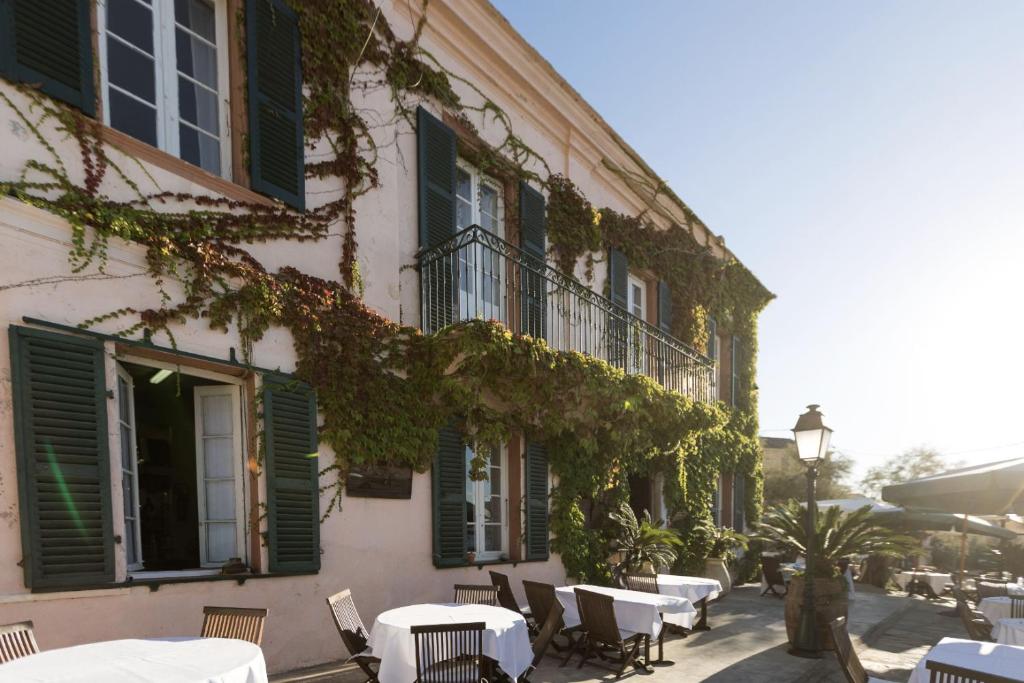 un edificio con mesas, sillas y hiedra. en Hotel-Restaurant Le Vieux Moulin en Centuri