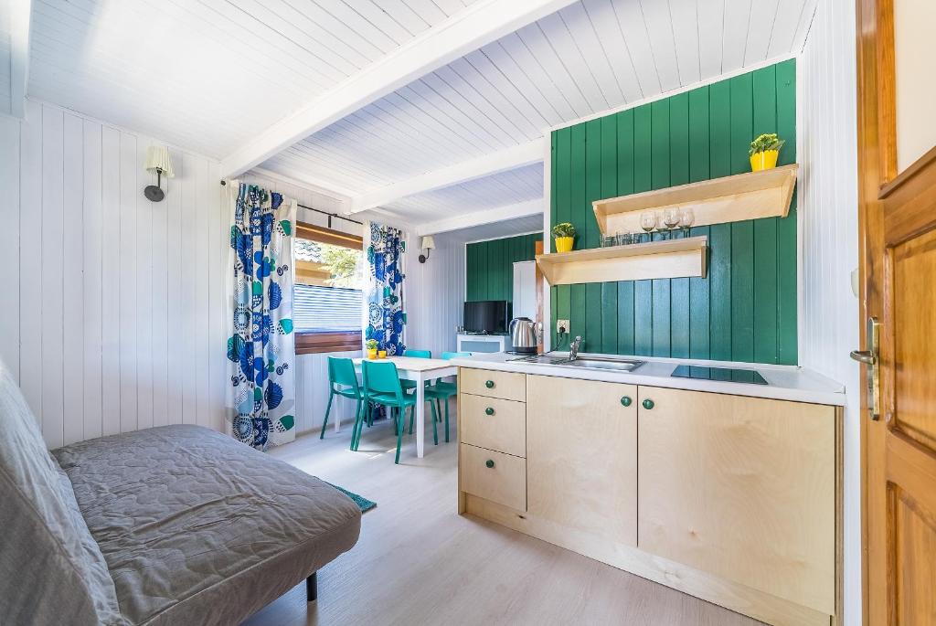 uma cozinha com paredes verdes e uma mesa num quarto em DRAGA AM Konkel em Jastarnia