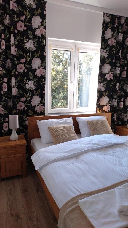 two beds in a bedroom with flowers on the wall at Tabago Studio 11 in Nysa