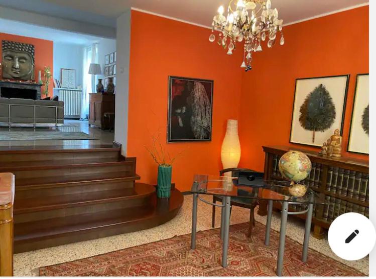 una sala de estar con paredes de color naranja y una lámpara de araña. en Suite Lago blu en Gravedona