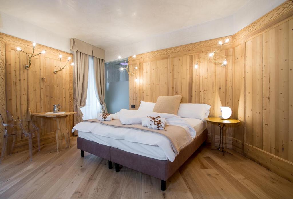 - une chambre avec un grand lit et des murs en bois dans l'établissement Hotel Orso Grigio, à Cavalese