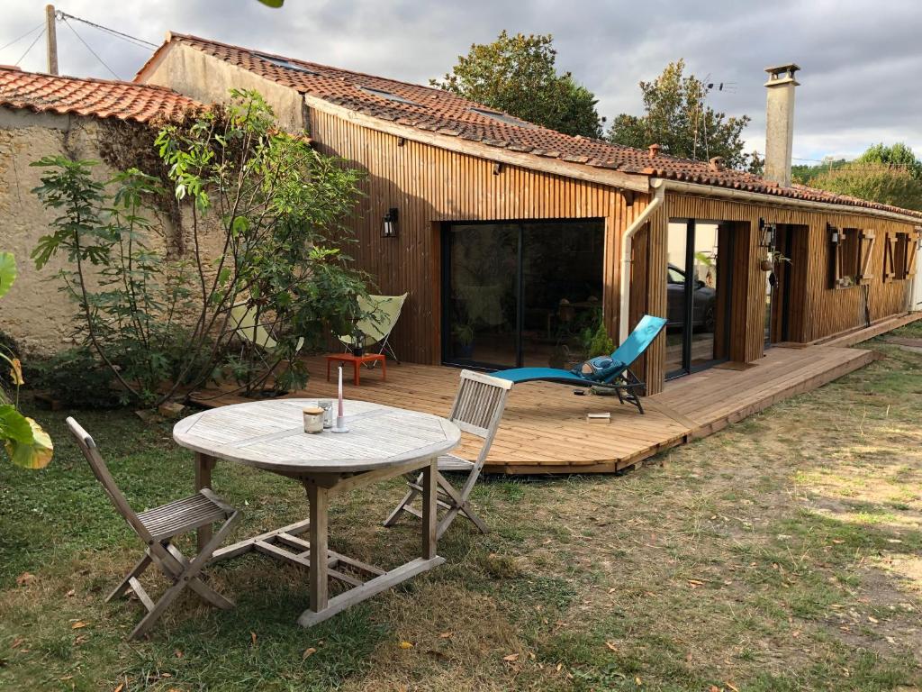 une terrasse en bois avec une table et des chaises devant une maison dans l'établissement Uluwatu - cottage cosy, à Saint-Laurent-de-Médoc
