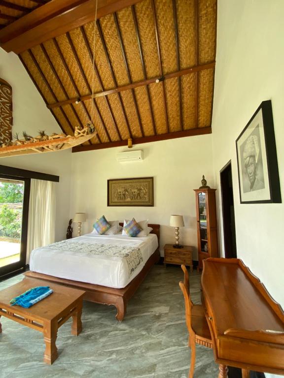 Schlafzimmer mit einem Bett, einem Tisch und einer Bank in der Unterkunft Puri Ayu in Canggu