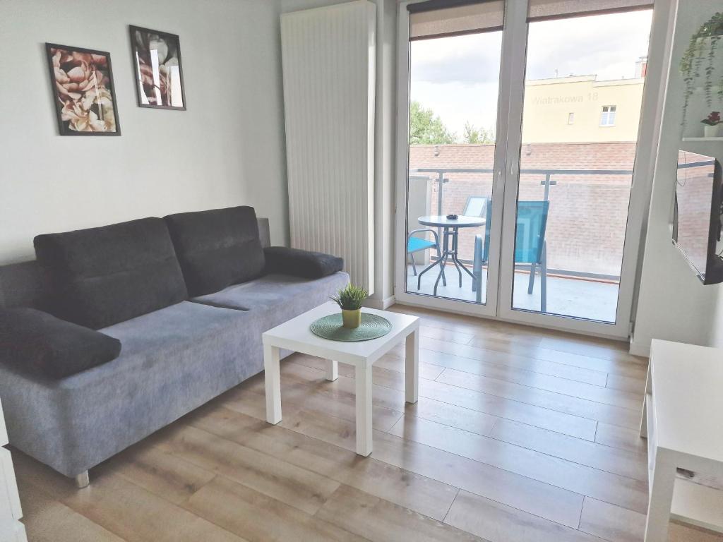 ein Wohnzimmer mit einem Sofa und einem Tisch in der Unterkunft Urban Jungle - Silver Apartment in Białystok