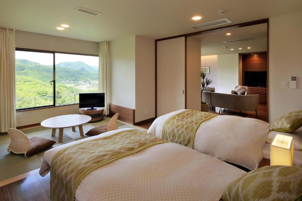 a hotel room with two beds and a table at 仙台秋保温泉 篝火の湯 緑水亭 in Sendai