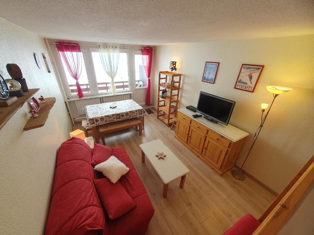 salon z czerwoną kanapą i telewizorem w obiekcie La Mongie, Studio pieds des pistes, parking intérieur privé w mieście La Mongie