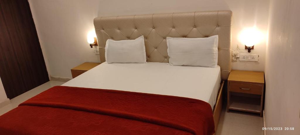 sypialnia z dużym białym łóżkiem z czerwonym kocem w obiekcie Khajurāho Hostel w mieście Khajuraho