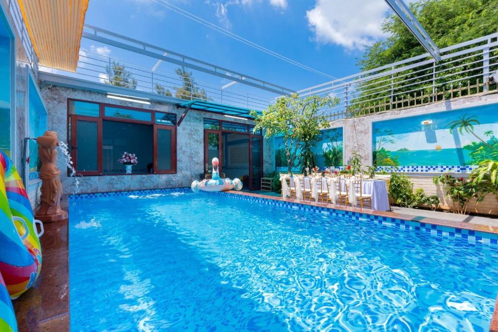 - une piscine avec une femme assise à côté d'une maison dans l'établissement Ngọc Thị Villa, à Vung Tau