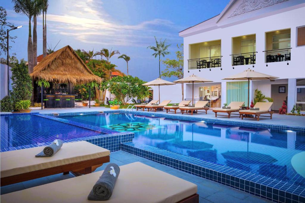 a pool at a resort with chairs and umbrellas at Sala Siem Reap Hotel in Siem Reap