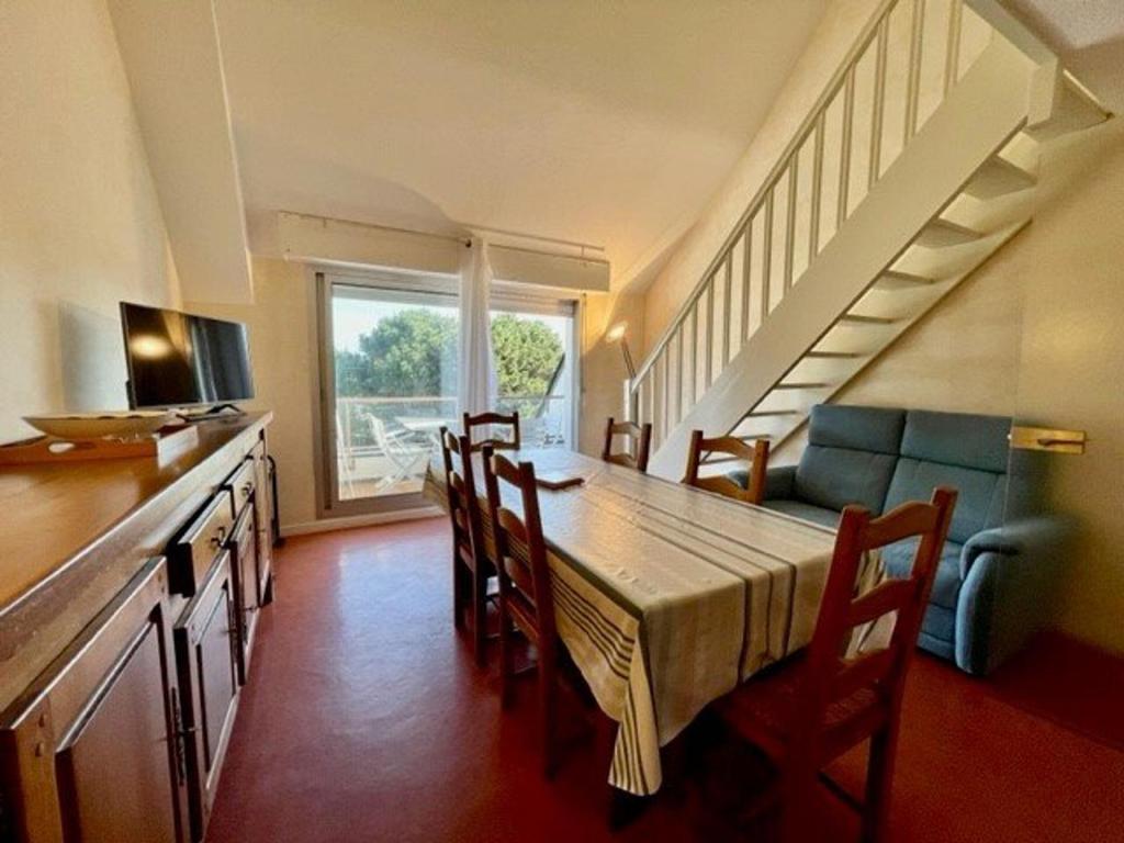 a dining room with a table and chairs and a staircase at Appartement Quiberon, 3 pièces, 5 personnes - FR-1-478-75 in Quiberon