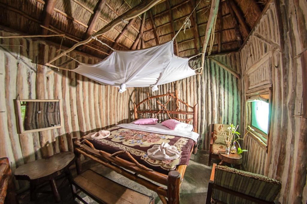 1 dormitorio con cama con dosel en una habitación de madera en Dave the Cave Eco Lodge and Cultural Campsite en Rubirizi