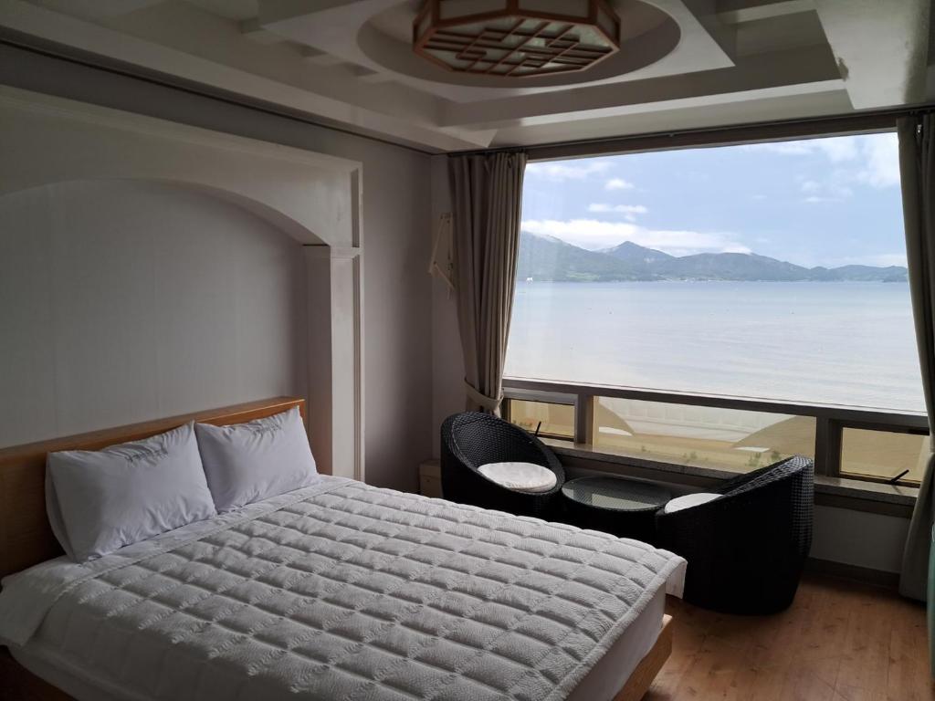 1 dormitorio con cama y ventana grande en Namhae Beach Hotel, en Namhae