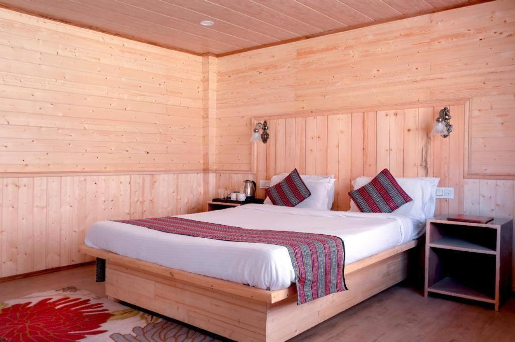 a bedroom with a bed in a wooden room at Keerong Cottages Lachung in Lachung